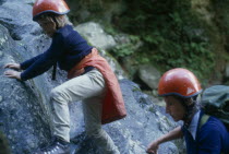 Woman and child rock climbing wearing red safety helmets in North Wales