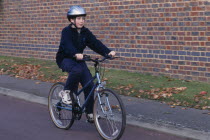 Child riding bicycle wearing safety helnet.