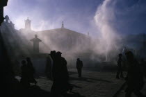 Jokhung Square.  People silhouetted in sunlight through smoke.