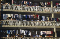 Laundry hanging on apartment balconies in the Xishuangbana area with residents looking down on street.