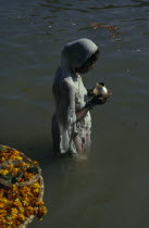 Hindu woman praying waist deep in the water of the River Ganges.