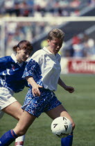 Two female footballers playing during an international match between England and Iceland