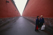 Two women standing between red walls