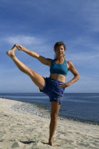 Woman performing a yoga pose on a sandy beach