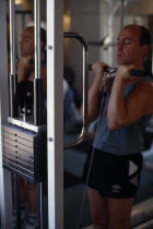 Man working on biceps on weight machine.