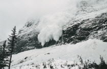 Avalanche of snow crashing down steep mountainside.
