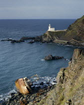 North Devon-Hartland Point lighthouse next to rugged coast with a shipwrecked boat
