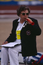 Female official blowing horn to warn that competitor is about to throw javelin.