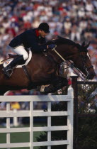 French rider Herve Godignon competing in the 1993 Hickstead Derby  clearing white gates on bay horse.