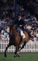 Nick Skelton competing in the Hickstead Derby  on bay horse approaching fence  not in picture  with crowds in grandstand behind.