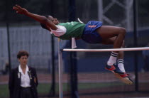 Competitor in schools high jump event arching backwards over bar.