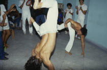Local men in animated poses of martial arts  inside a small room with spectators.