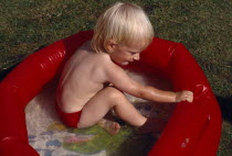 Young child playing in red padling pool