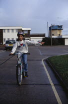 Girl wearing safety head gear  riding bike giving a hand signal.