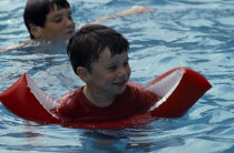 Child wearing water wings in swimming pool