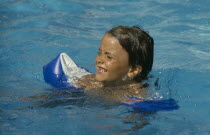 Young girl wearing water wings in swimming pool