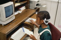 Eight year old black girl doing a report for school on the computer.