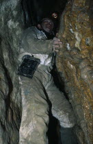 Man climbing in Limestone Area with spotlight on his head.