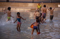 Multi-racial group of young children playing in paddling pool