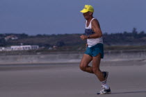 Jersey . St Ouens Bay. Elderly man jogging on sandy beach