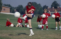 Young boy kicking football during coaching derby.