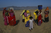 Brightly dressed Rajasthani women and children carrying loads on their heads. Asia Asian Bharat Female Woman Girl Lady Inde Indian Intiya Kids
