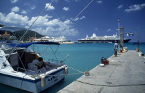 Harbour view with man standing on stone jetty and cruise ships behind.  Moored boat in the foreground with person sitting in shade on deck.Jamaican Male Men Guy West Indies