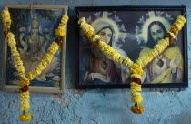 Framed pictures of Hindu and Christian iconography hung with marigold flower garlands.Asia Asian Bharat Inde Indian Intiya Religion Religion Religious Christianity Christians Religion Religious Hindu...