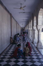 Sikh pilgrims sitting on long  colonnaded temple passage-way with black and white chequered pattern floor.family Asia Asian Bharat Inde Indian Intiya Kids Religion Religion Religious Sihism Sikhs