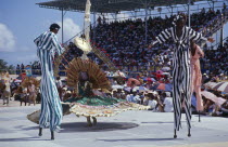 Crop Over sugar cane harvest festival.  Grand Kadooment carnival parade stilt walkers in striped costume.Barbadian West Indies