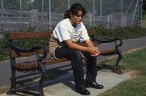 Teenage girl on park bench looking sad and thoughtful.