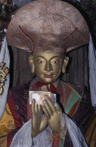 Buddhist temple statue of high ranking lama with money placed in its hands and draped with white  silk kata as mark of esteem.