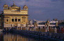 Pilgrims on causeway known as the Guru s Bridge leading to the Golden Temple reflected in rippled surface of pool below.Asia Asian Bharat Inde Indian Intiya Religion Religious