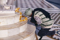 Golden Temple.  Barefoot Sikh pilgrim kneeling at shrine to pray with garland of marigold flowers laid out on marble steps.worship Asia Asian Bharat Inde Indian Intiya One individual Solo Lone Solita...