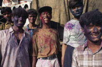 Group of young men with their faces covered with coloured powder paint dyes during Holi Festival