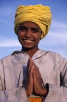 Portrait of smiling Sikh boy wearing yellow turban making gesture of greeting or namaste with his hands.Asia Asian Bharat Happy Immature Inde Indian Intiya Kids One individual Solo Lone Solitary Reli...