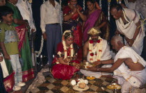 People standing around sitting couple wearing traditional wedding dress.Asia Bharat Classic Classical Historical Inde Indian Intiya Marriage Older Religion Religion Religious Hinduism Hindus