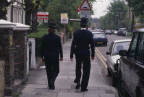 Policeman and woman on the beat  walking along city pavement.