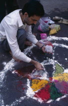 Painting patterns on ground as base for bonfire during Hindu Holi Festival.