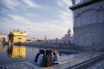 Group of Sikh men sitting on marble walkway surrounding sacred pool within the Golden Temple complex.Asia Asian Bharat Inde Indian Intiya Male Man Guy Religion Religion Religious Sihism Sikhs