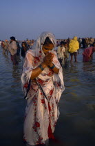 Woman pilgrim praying during three day Sagar bathing festival at point where the Ganges joins the sea.  Other people in water behind her.3 Asia Asian Bharat Female Women Girl Lady Inde Indian Intiya...