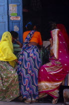 Women with backs to camera sitting at shop entrance.Asia Asian Bharat Female Woman Girl Lady Inde Indian Intiya Rajasthani Store