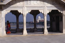 View towards the Taj Mahal seen through covered  colonnaded walkway with woman wearing red and purple sari on left hand side. 1631-1653  17th C. Seventeenth century  Mughal  funerary  mausoleum   tom...