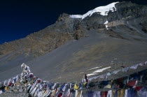 Prayer flags hanging at the top of the pass with snow covered mountain peak behind. Asia Asian Nepalese Religion Religious Scenic