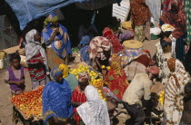 Market.  Women in brightly coloured dress at fruit stall.
