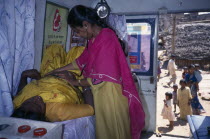 Female health worker examining a pregnant woman in a mobile clinic.  Children and woman seen outside through open door.Asia Asian Bharat Cell Cellular Female Women Girl Lady Inde Indian Intiya Kids