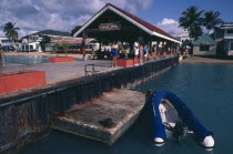 Philipsburg.  Quayside with tourists looking in the water and the Captain Hodge Wharf behind.  Dingy moored in the foreground.Caribbean Holidaymakers Tourism West Indies