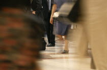 Cropped shot of business man in suit standing still surrounded by crowds in blurred movement.