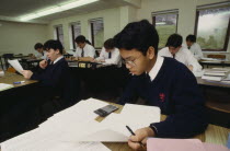 Asian teen boy using electronic calculator in class