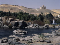 Feluccas on the Nile. View of Felucca sailing among the boulders off  Elephantine Island with the Mausoleum of the Aga Khan in the background.History Middle East North Africa Scenic